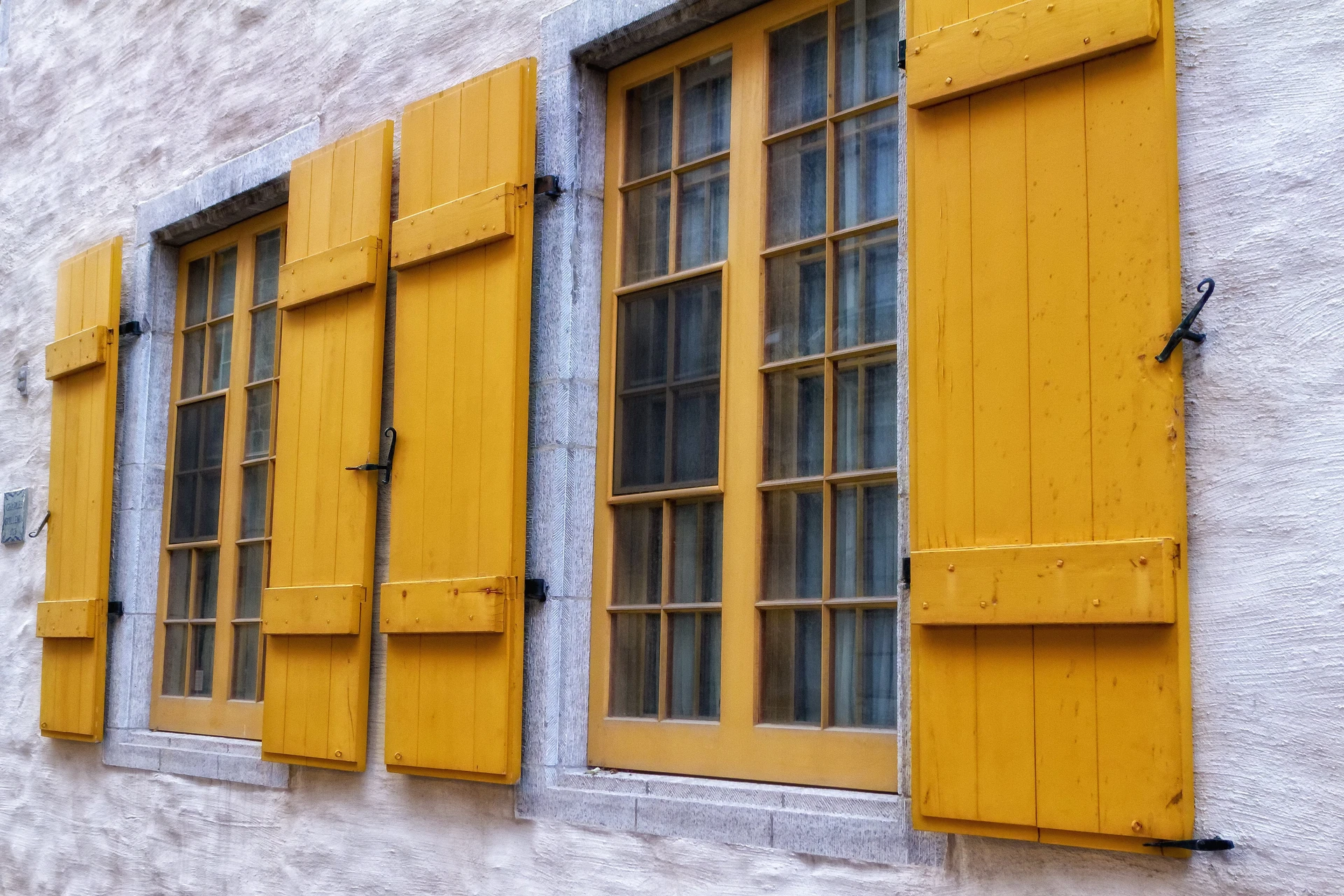 Façade extérieure d'un bâtiment traditionnel avec fenêtres à carreaux et volets en bois peints en jaune vif